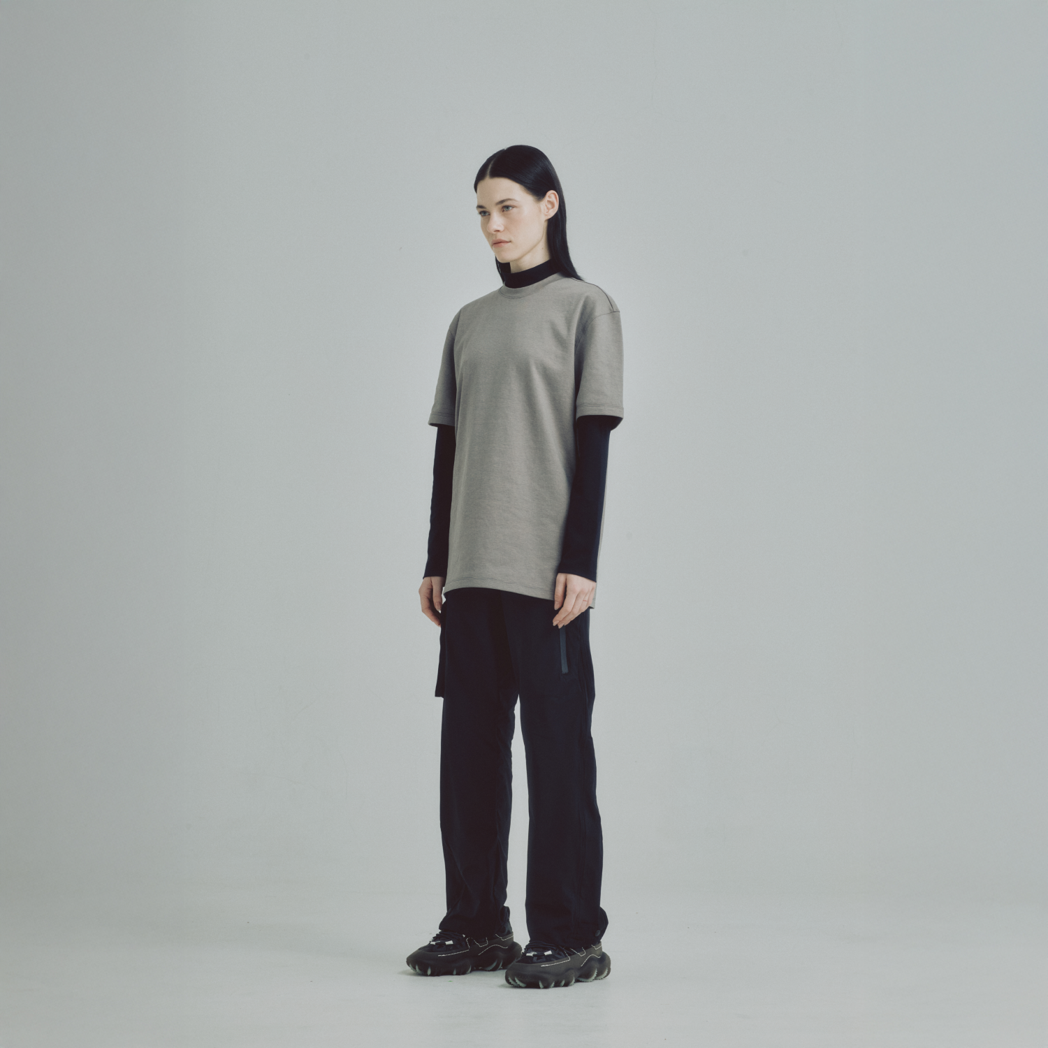 Mujer usando pantalón Iron negro y t-shirt gris de Remanence, look techwear funcional y minimalista.