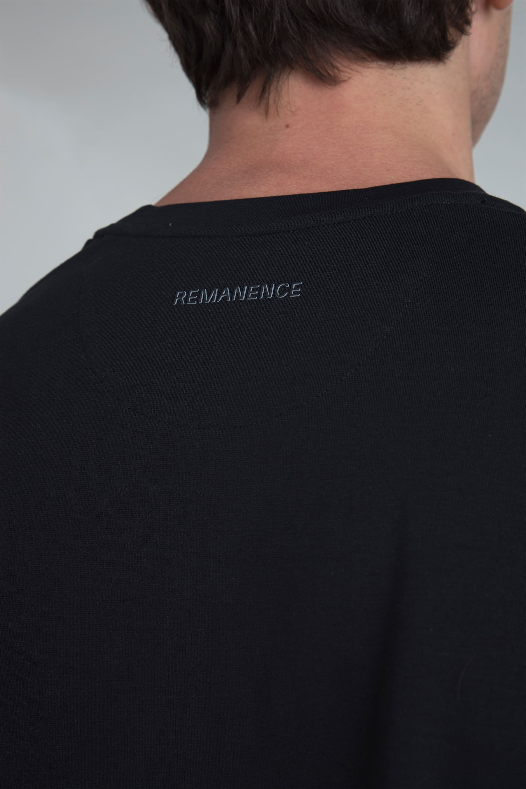 detalle logo Remanence en parte posterior del cuello de camiseta negra boxy fit