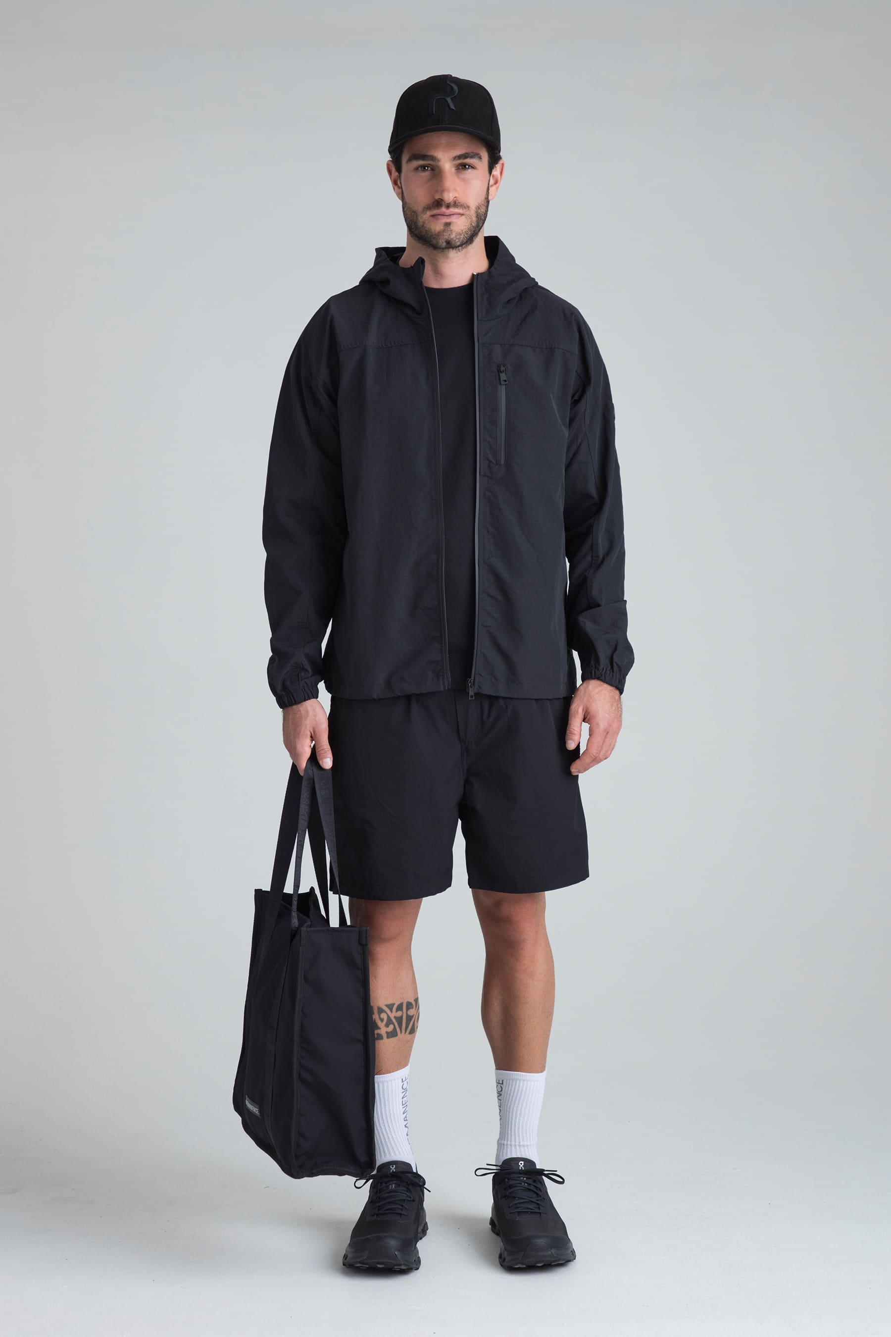 Hombre con chaqueta negra y shorts negros remanence