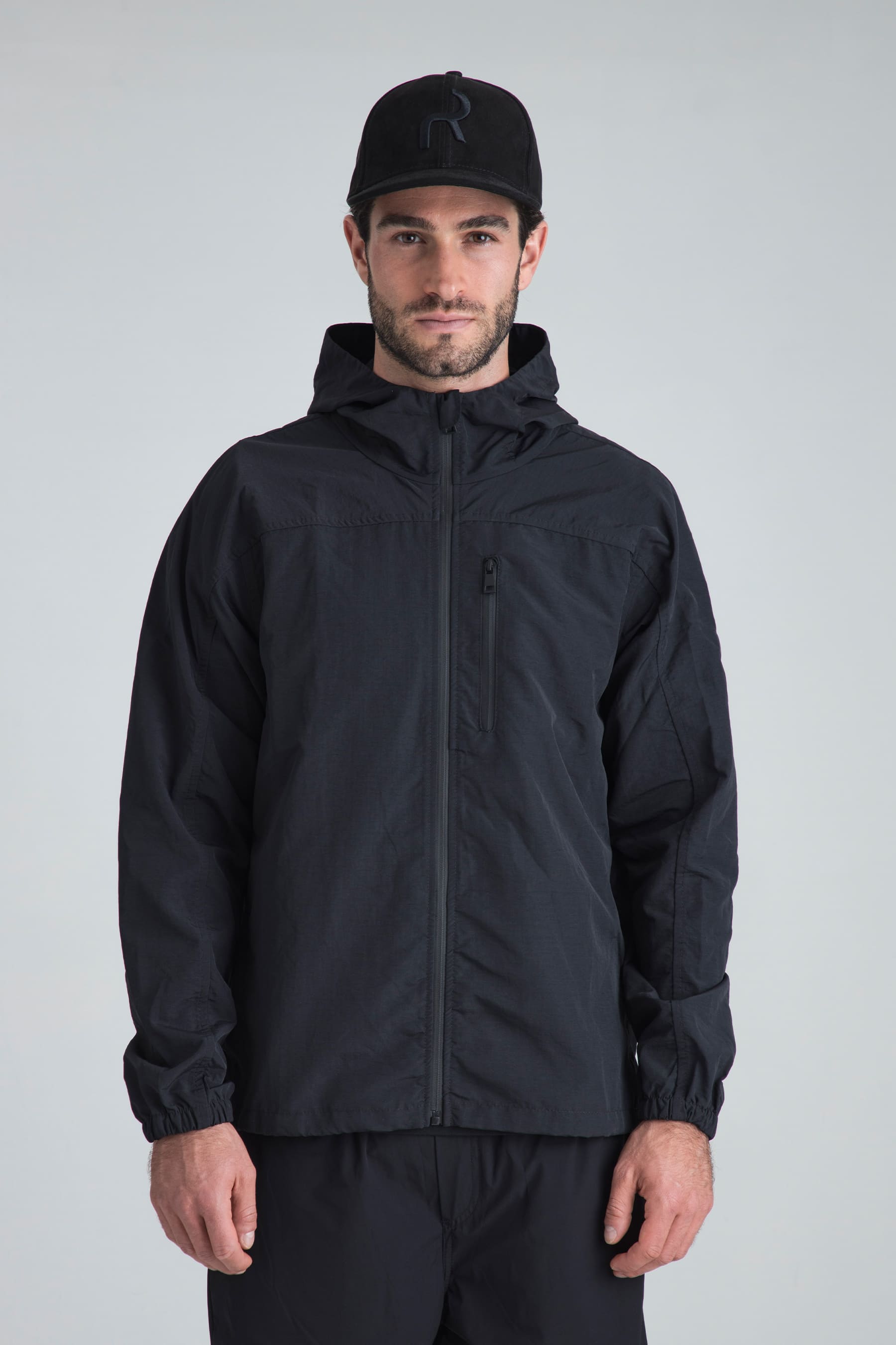 Hombre con chaqueta deportiva negra y gorra negra para running