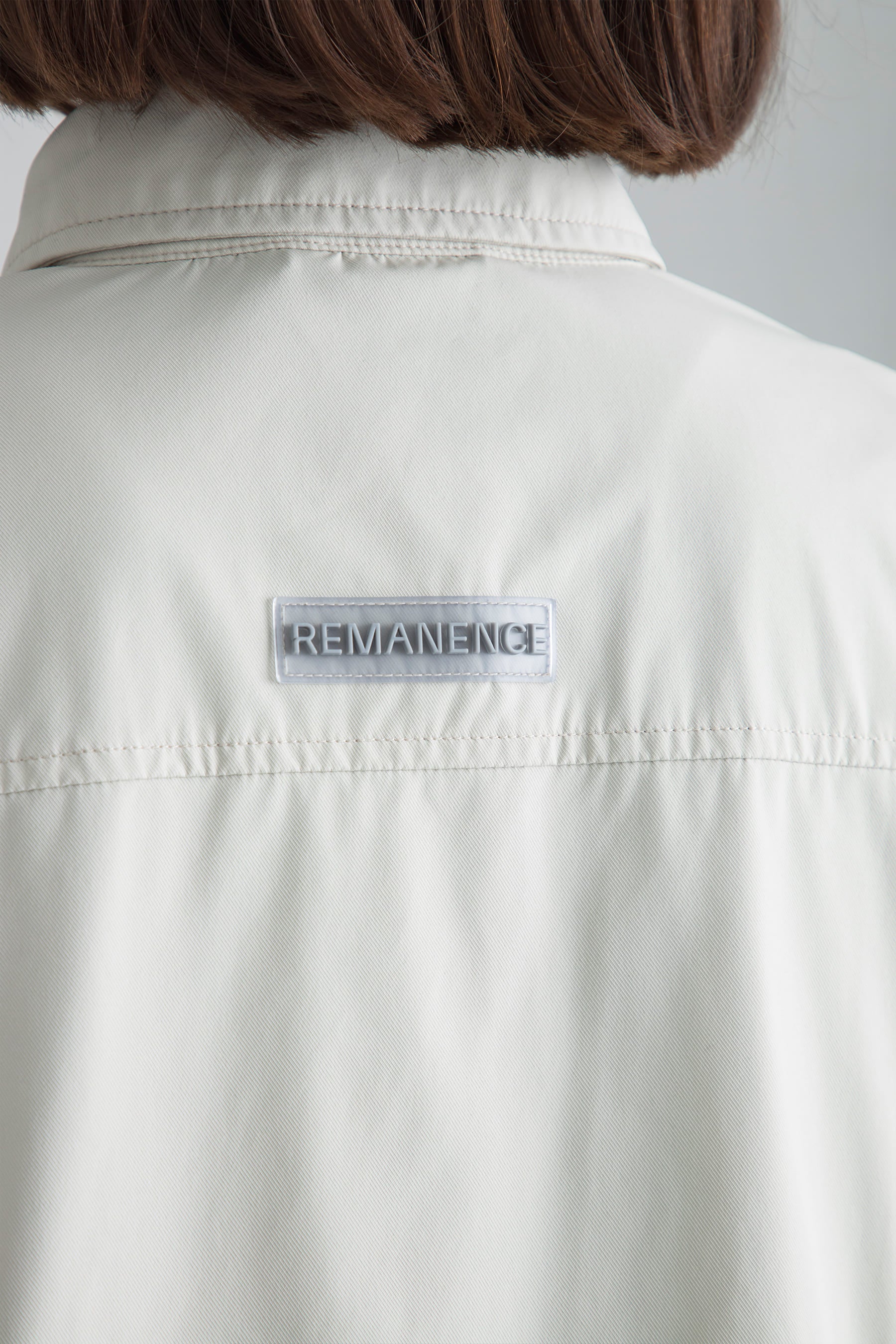 Detalle logo posterior en chaqueta arena para mujer