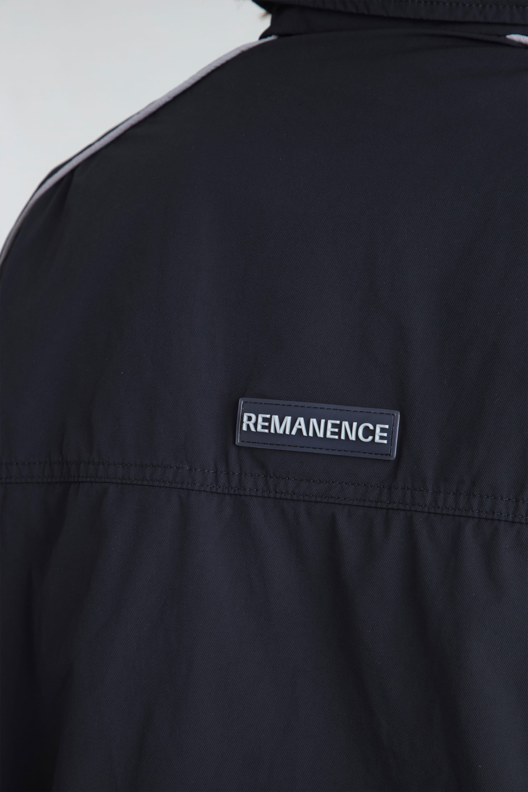 Detalle de logo Remanence en la chaqueta negra para muje