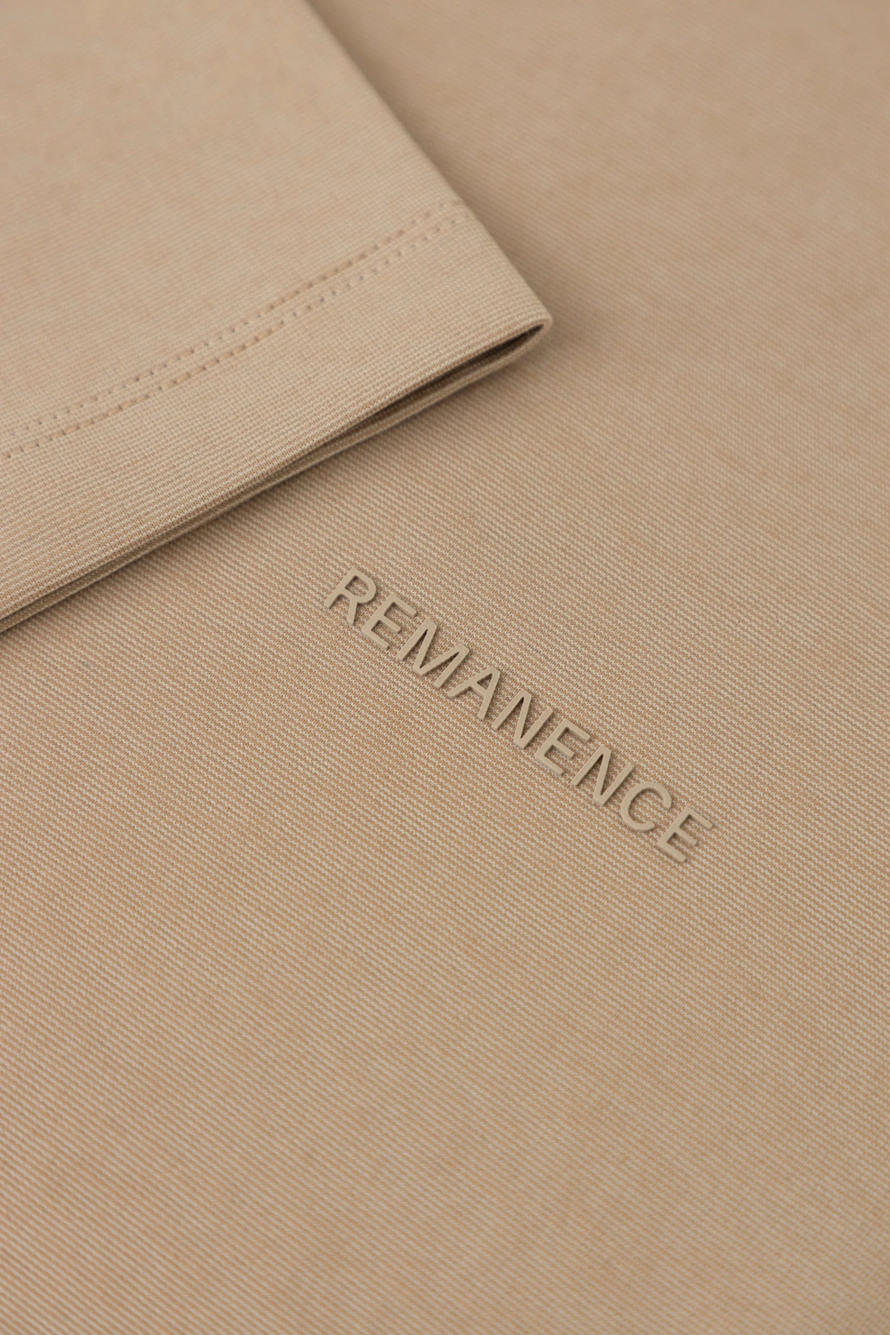 Detalle de costura de manga en camiseta café claro Remanence para hombre.