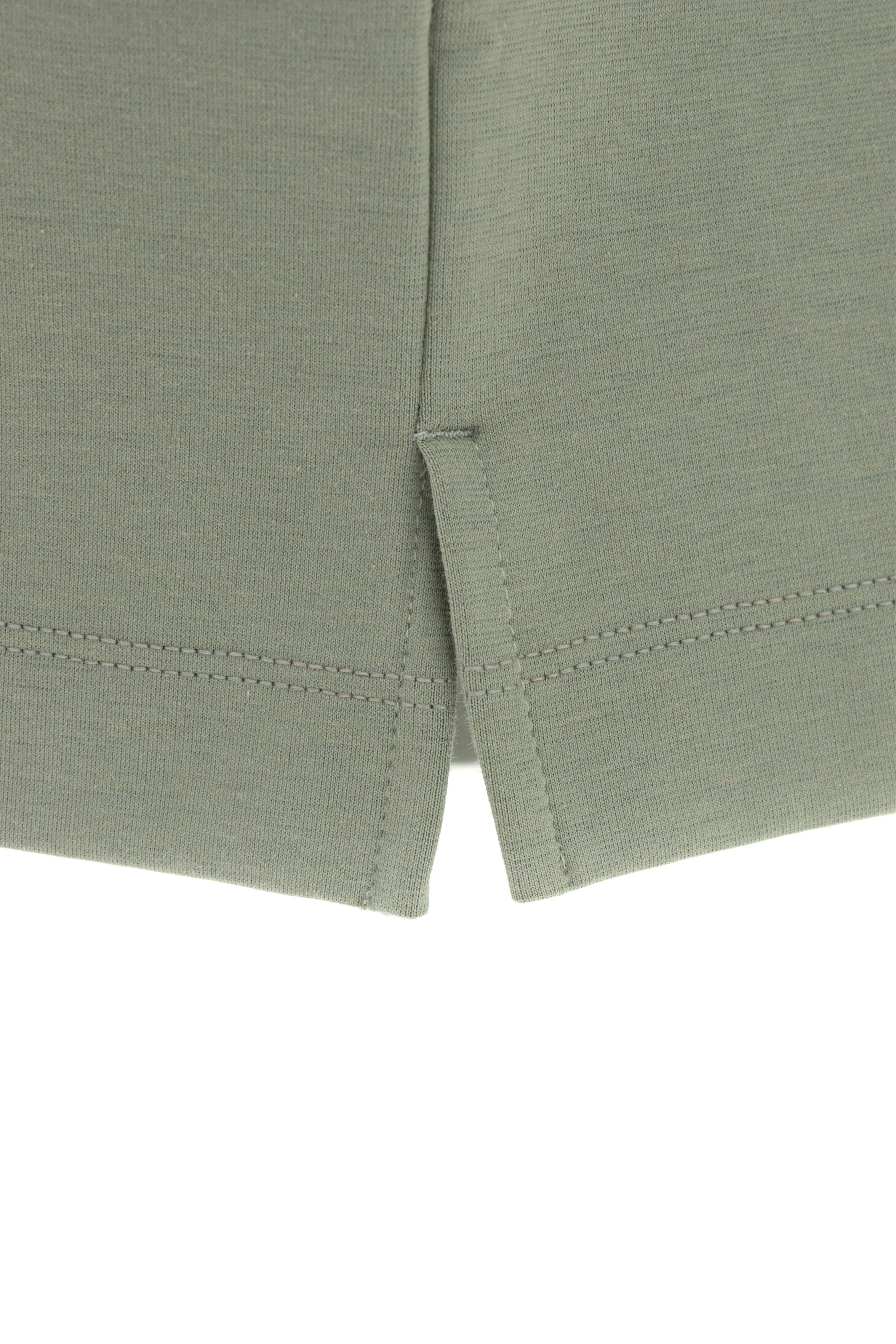 Detalle de aberturas laterales en camiseta verde grisáceo para hombre semi fitted.