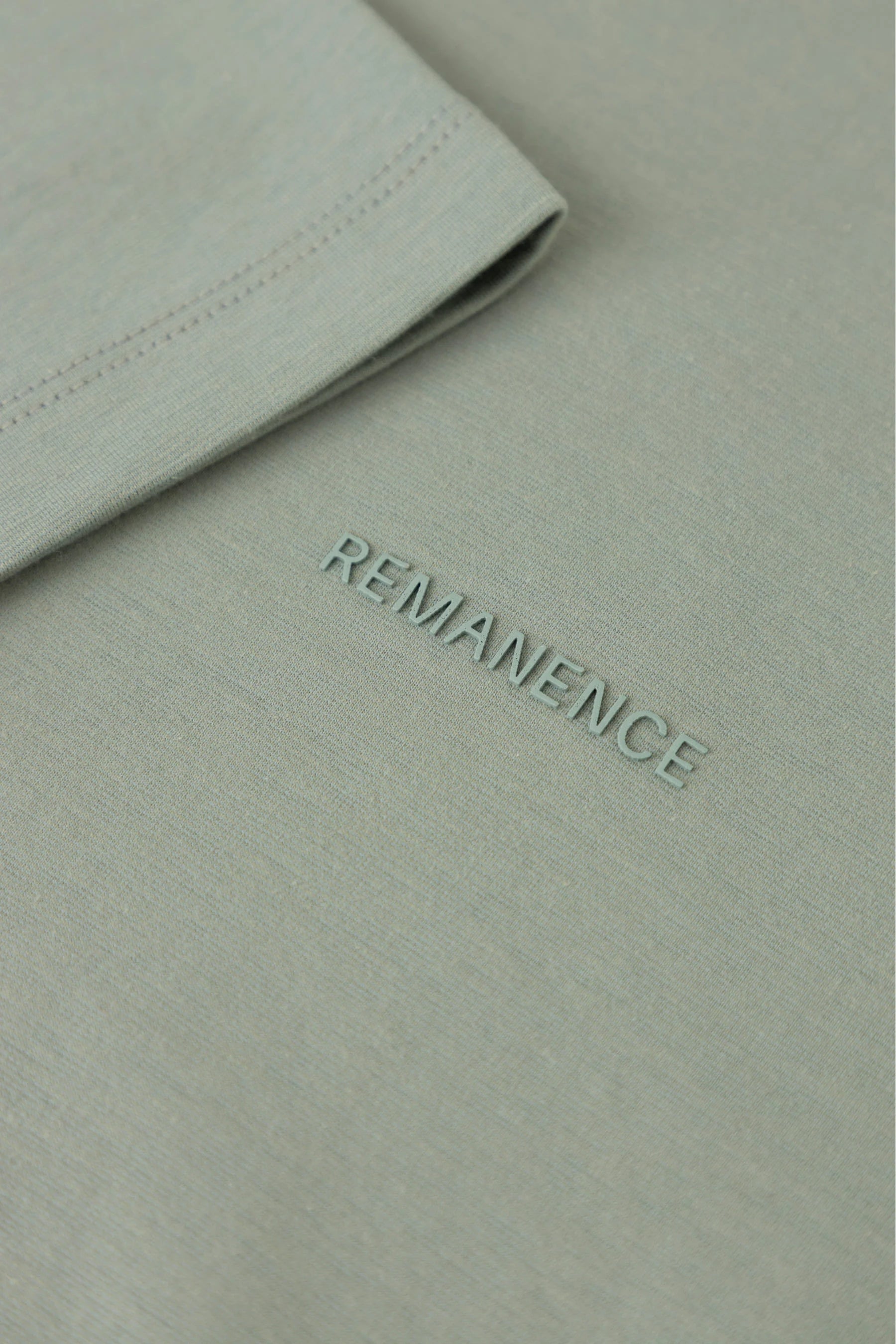 Detalle de costura de manga en camiseta verde grisáceo Remanence para hombre.