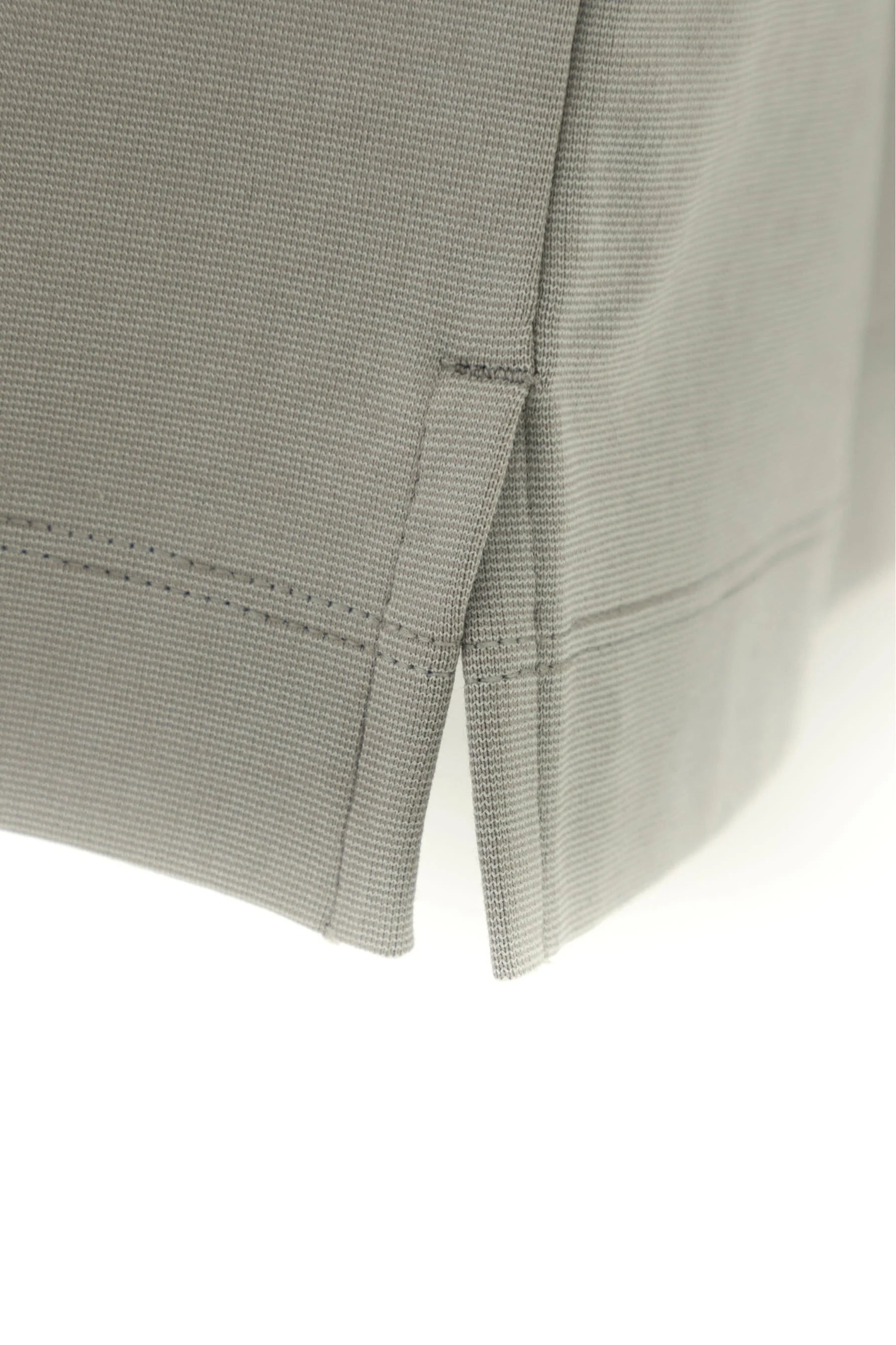 Detalle de aberturas laterales en camiseta gris claro para hombre semi fitted.