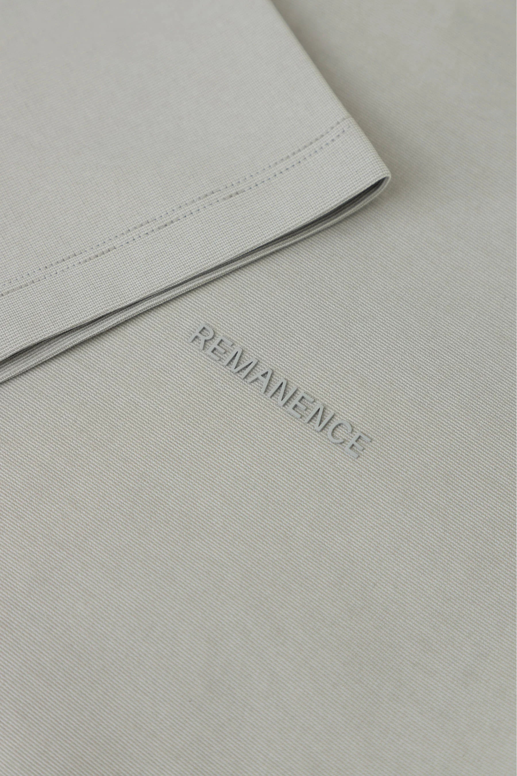 Detalle de costura de manga en camiseta gris claro Remanence para hombre.