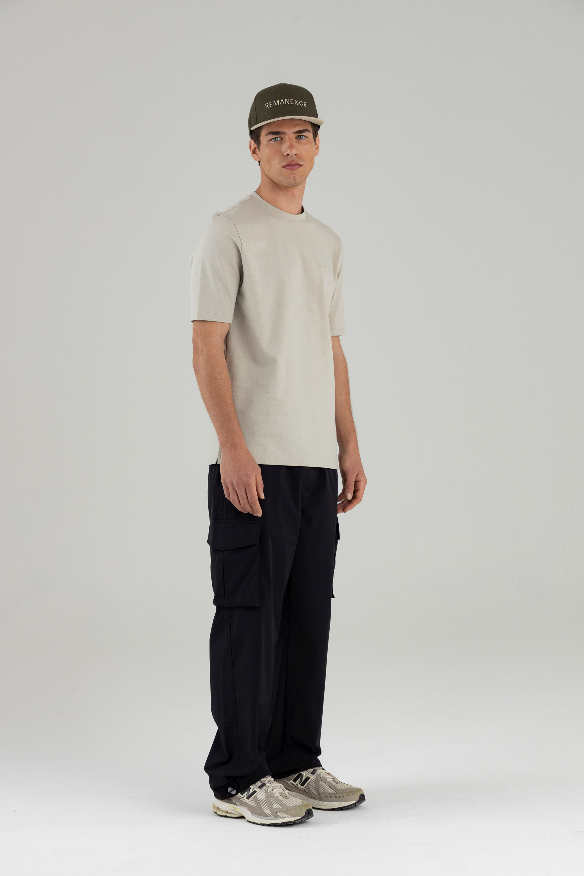 Hombre con camiseta arena Remanence y pantalón cargo negro, vista frontal de cuerpo completo.