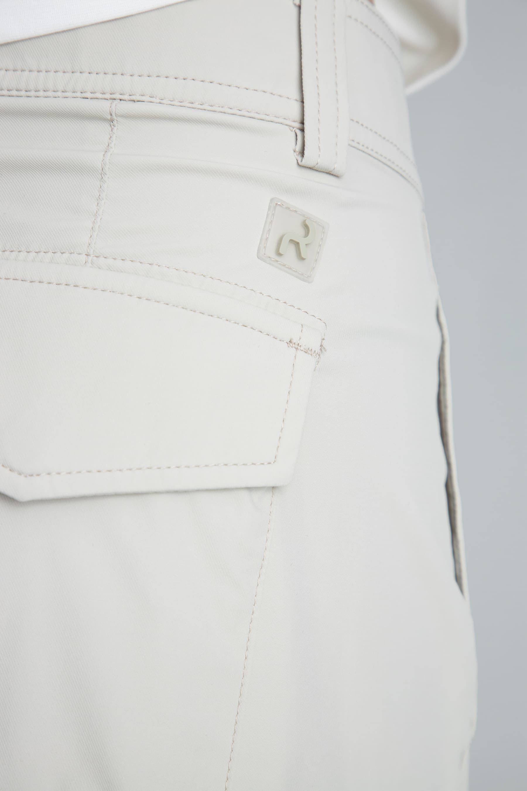 Detalle bolsillo posterior y logo discreto del pantalón recto arena para mujer