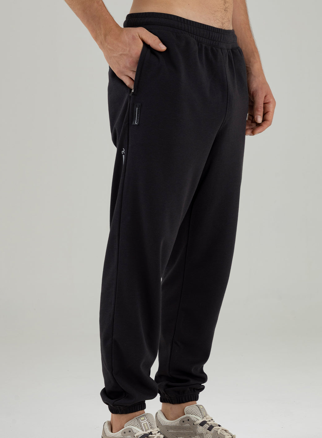 Modelo con pantalón jogger negro Remanence con ajuste holgado, bolsillos laterales y bota con elastico.