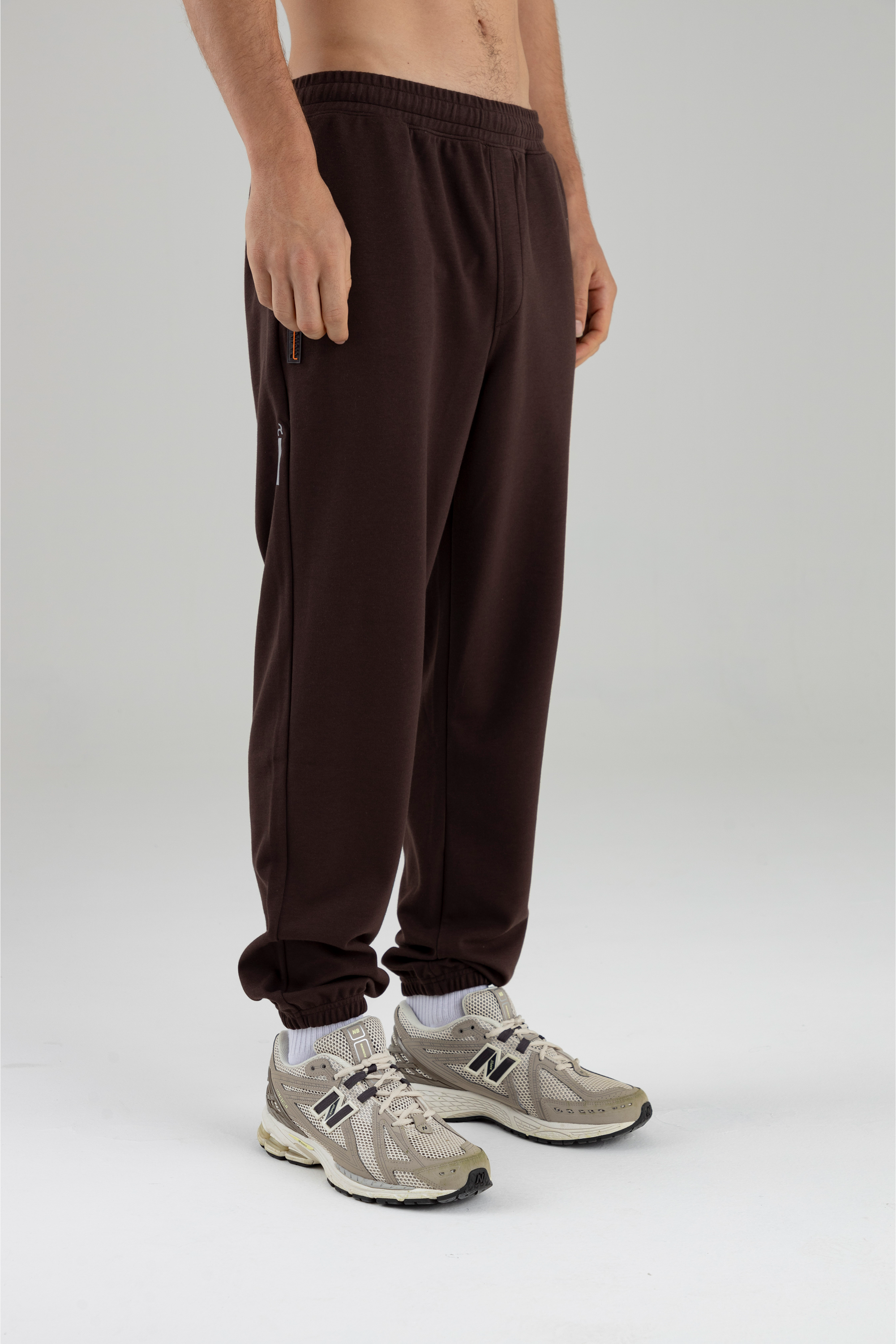 Vista diagonal del jogger café para hombre, mostrando bota elástica.