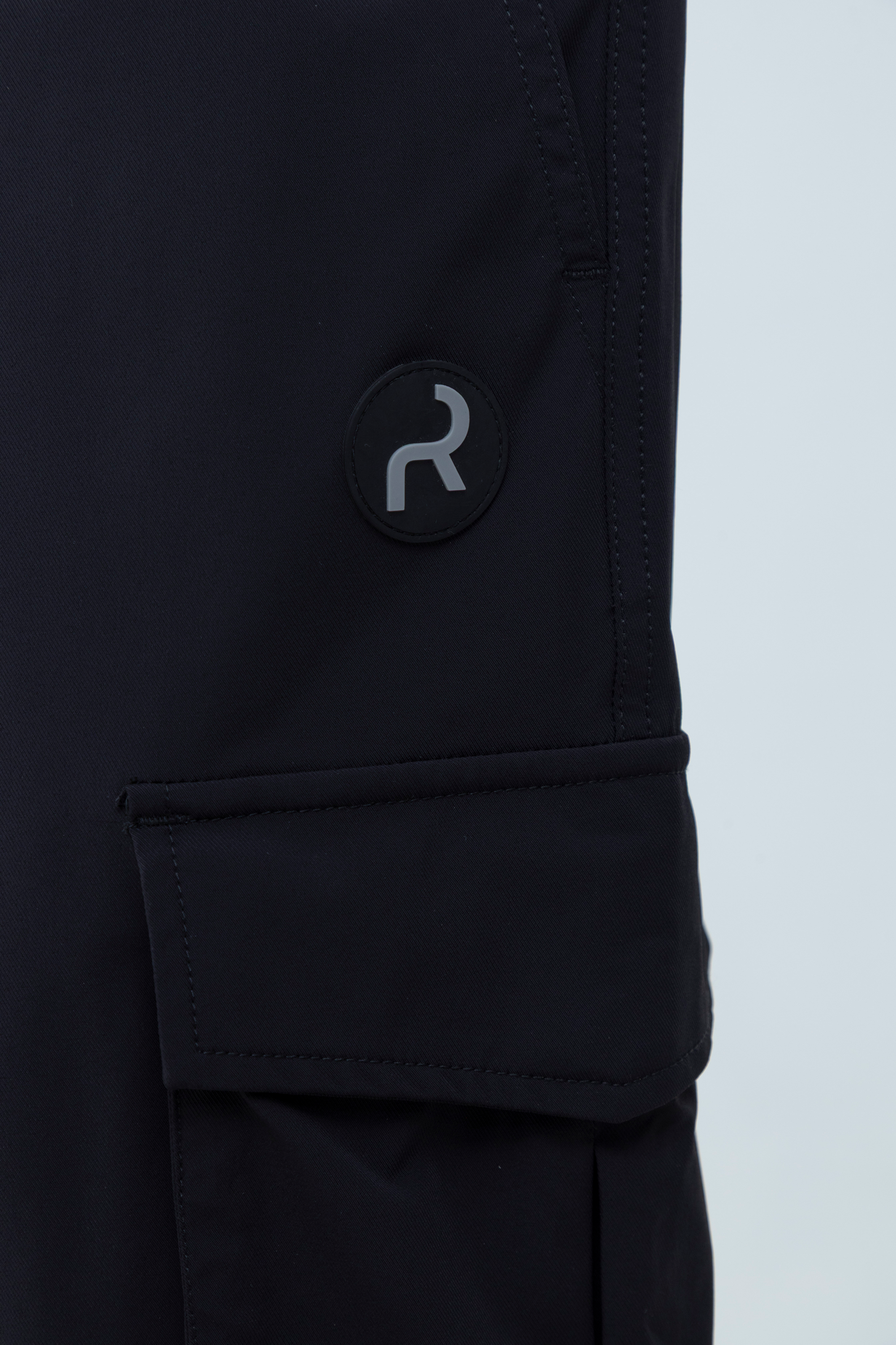 Detalle de bolsillo con broche y logo Remanence en aplique.