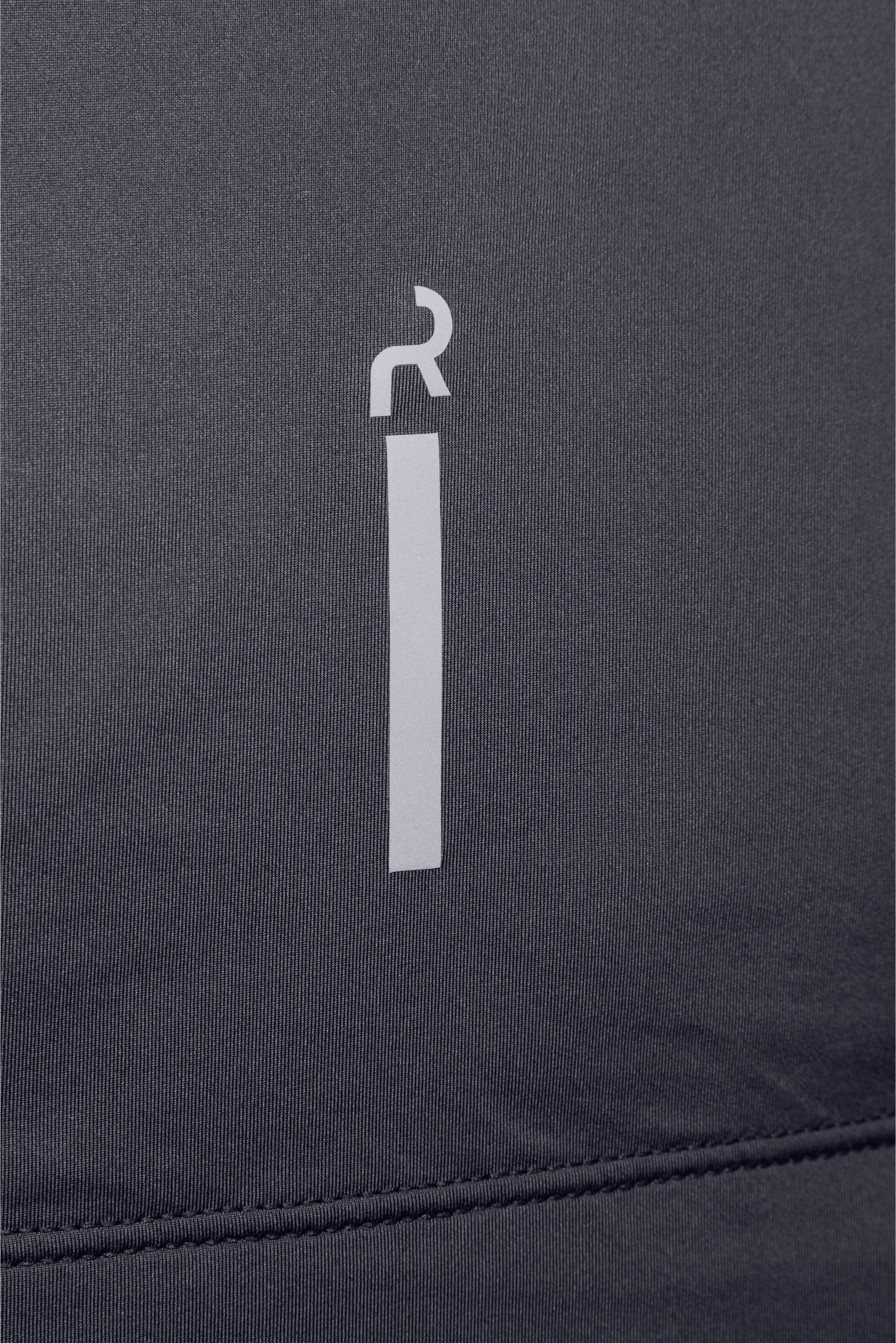 Close-up del logo vertical reflectivo en la parte inferior trasera de la camiseta.
