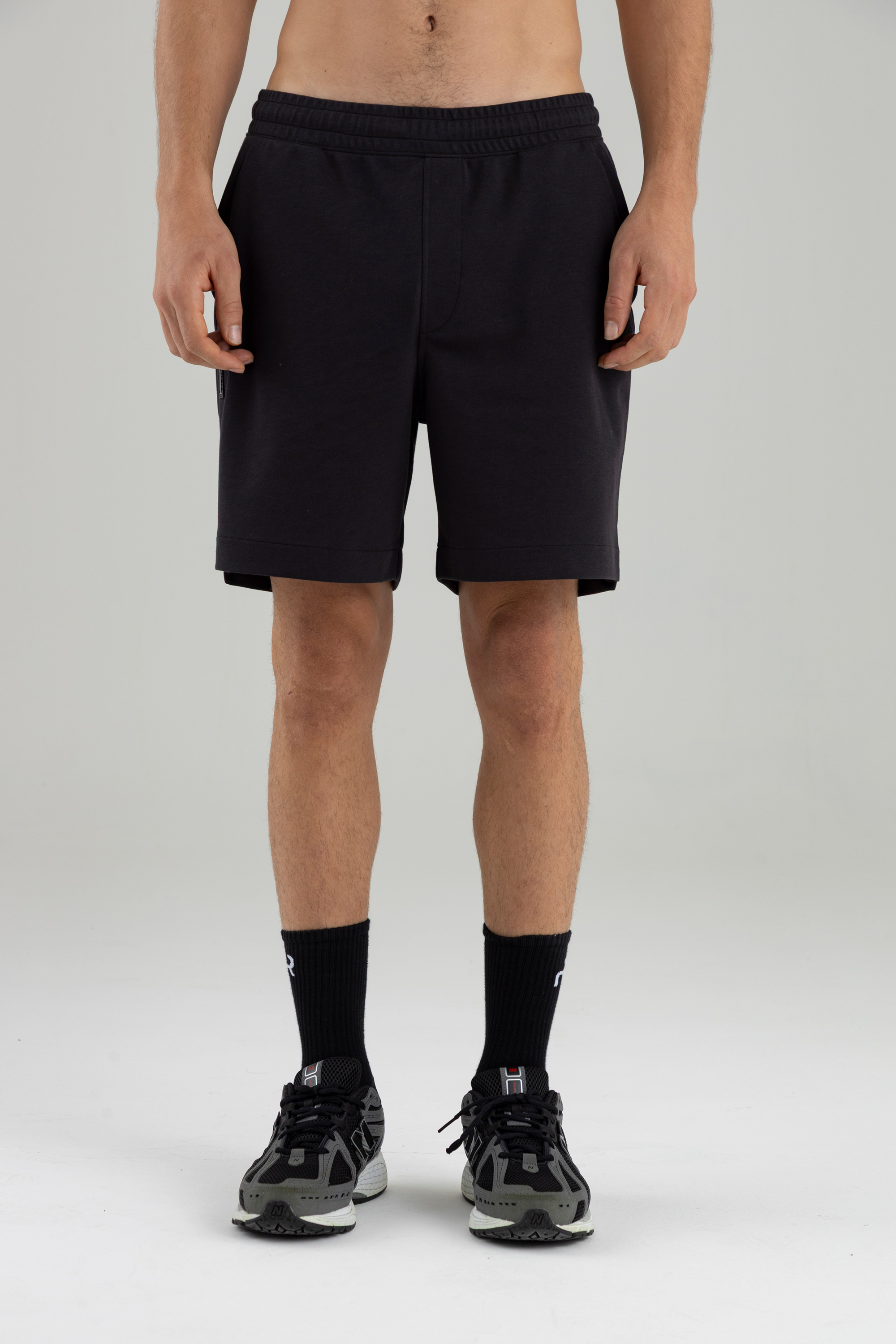 Hombre de frente usando short negro con pretina elástica.