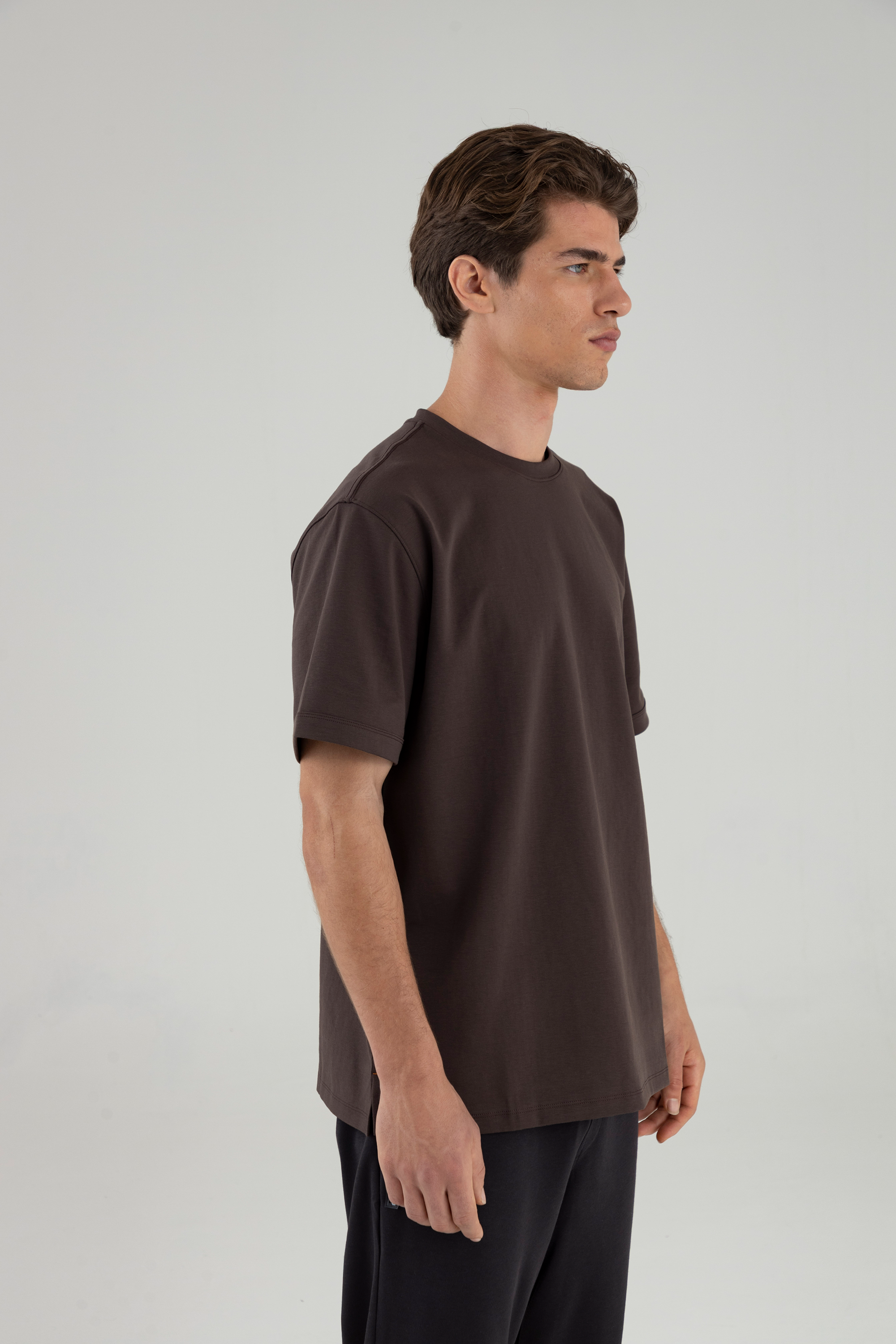 Hombre de perfil usando camiseta relaxed fit café.