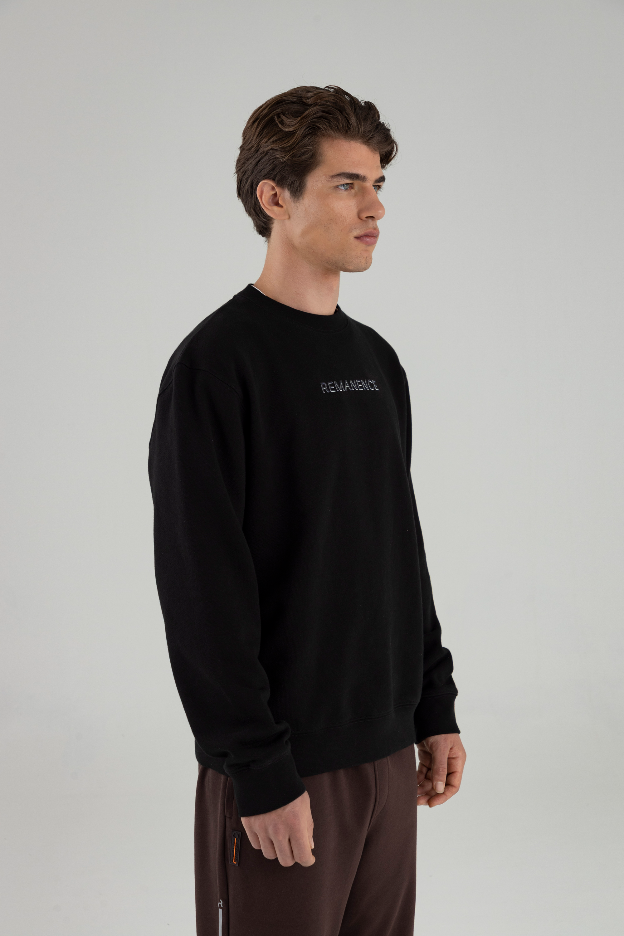 Hombre usando Crew Neck Verge negro, vista tres cuartos.